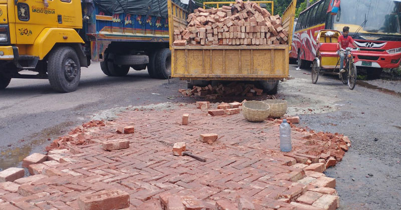 ভাঙাচোরা সড়ক জোড়াতালির কাজে দেওয়া হচ্ছে ইটের সলিং।